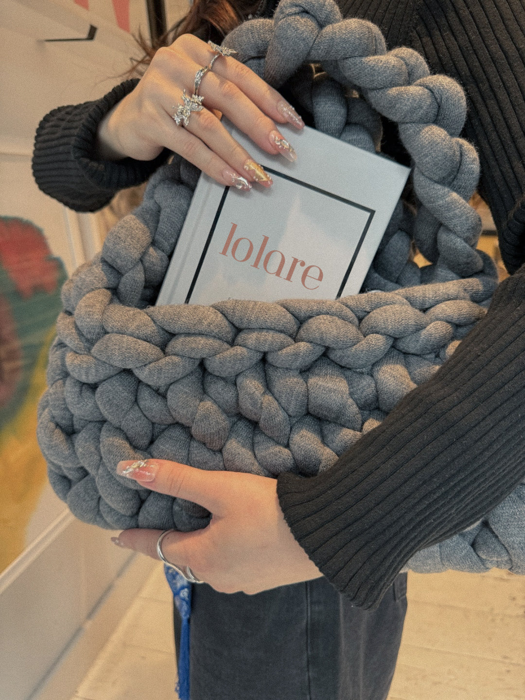 Person holding a textured gray bag with 'lolare' branding.